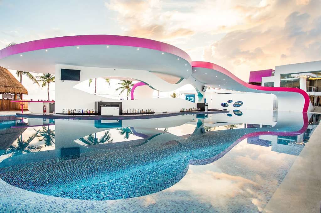 Curved swim-up pool bar at Temptation Cancun Resort at sunset